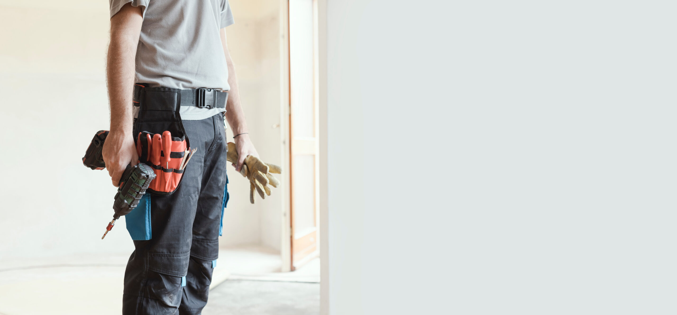 Professional repairman (handyman) standing and holding a drill, construction and home renovation concept. Offering professional handyman services